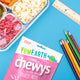 YumEarth Organic Chewys package with a lunch container, snacks, and coloring supplies on a blue background