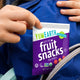 Kid pulling a YumEarth Fruit Snacks pouch from a backpack.