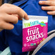Kid pulling a YumEarth Fruit Snacks pouch from a backpack.