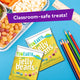 YumEarth Jelly Beans packs in yellow beside a lunch tray and colored pencils, with a “Classroom-safe treats!” label